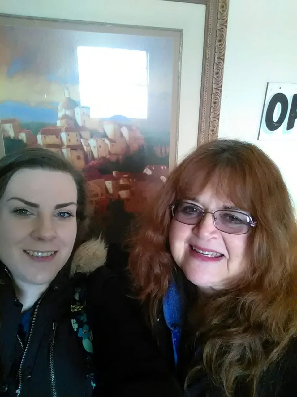 Rev. Berta Kay smiling beside a client in front of a painting in her reading room