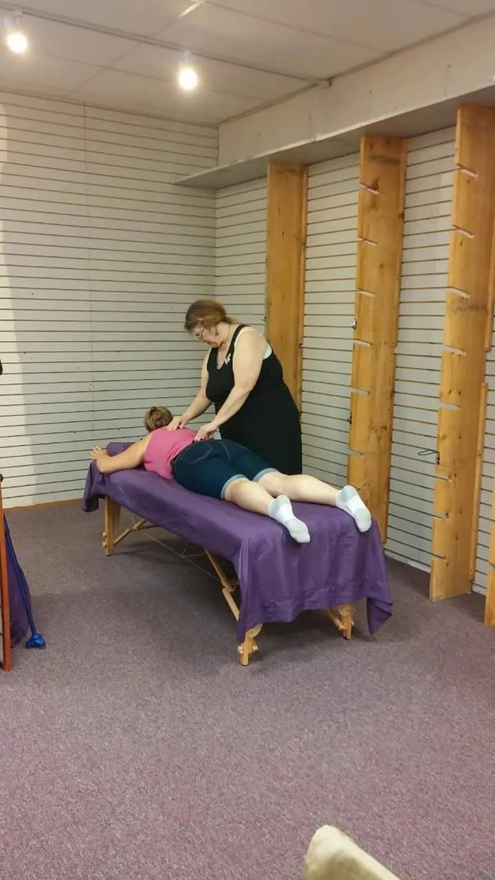 Rev. Berta Kay giving a Reiki session to a client on a purple massage table